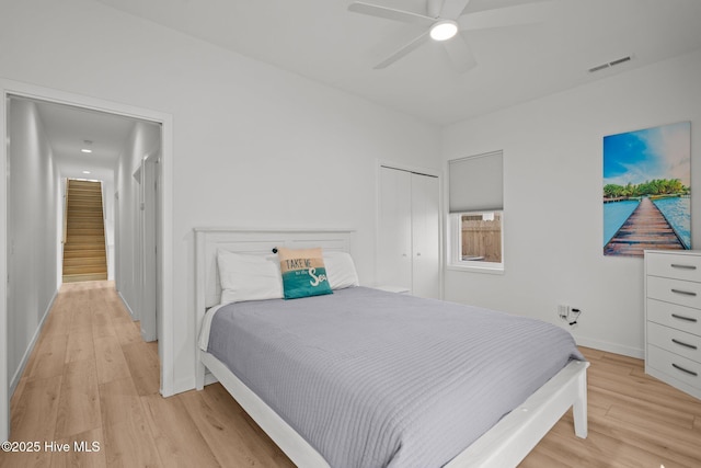 bedroom with ceiling fan, light hardwood / wood-style floors, and a closet