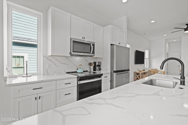 kitchen with sink, stainless steel appliances, and light stone countertops