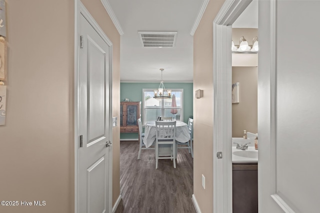 corridor featuring ornamental molding, dark wood-type flooring, sink, and a chandelier