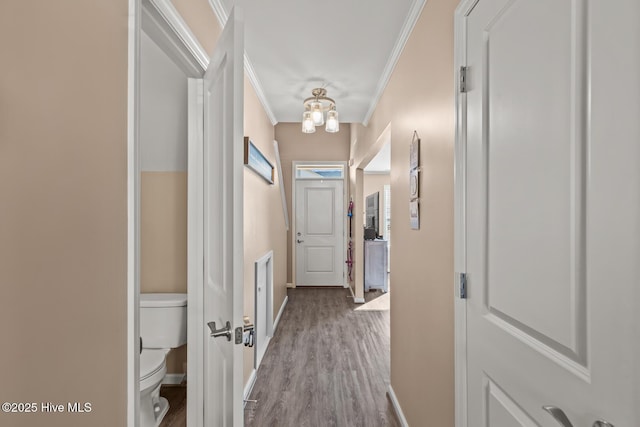 hallway featuring wood finished floors, baseboards, and ornamental molding