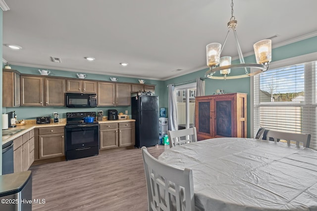 kitchen with crown molding, decorative light fixtures, black appliances, and a healthy amount of sunlight