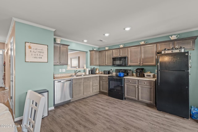 kitchen with light wood-type flooring, crown molding, sink, and black appliances