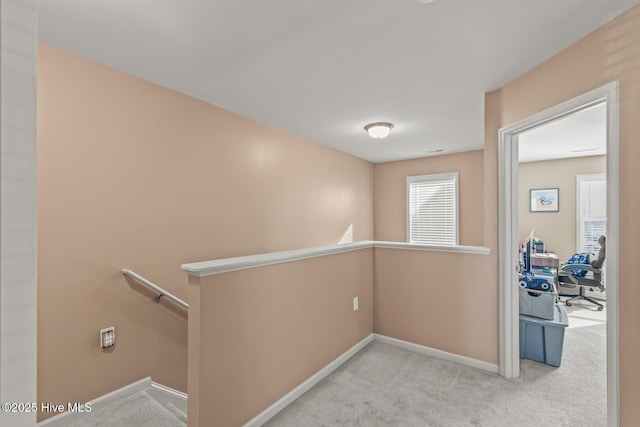 hallway with baseboards, an upstairs landing, and carpet flooring