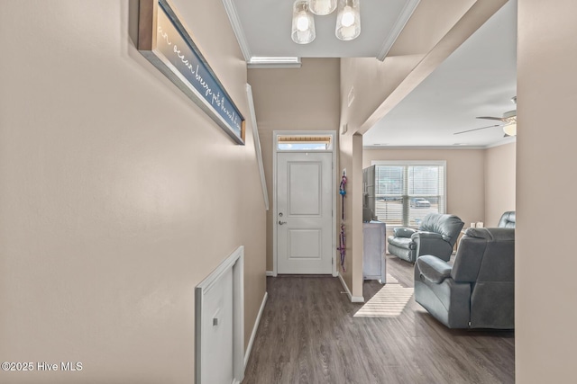 foyer featuring baseboards, wood finished floors, crown molding, and ceiling fan with notable chandelier