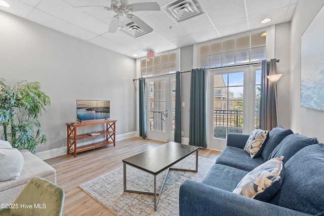 living room featuring ceiling fan, a drop ceiling, and light wood-type flooring