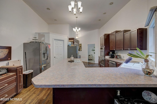 kitchen with appliances with stainless steel finishes, hanging light fixtures, hardwood / wood-style floors, dark brown cabinetry, and a chandelier