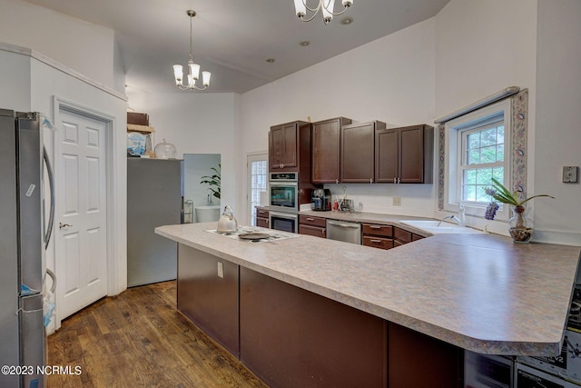 kitchen with dark wood-type flooring, dark brown cabinetry, sink, hanging light fixtures, and appliances with stainless steel finishes