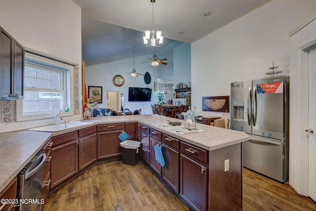 kitchen featuring decorative light fixtures, sink, kitchen peninsula, stainless steel appliances, and dark wood-type flooring