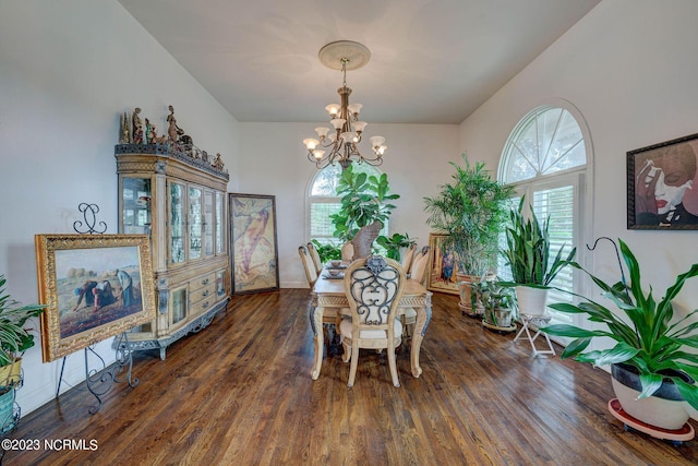 dining space with dark hardwood / wood-style flooring and an inviting chandelier