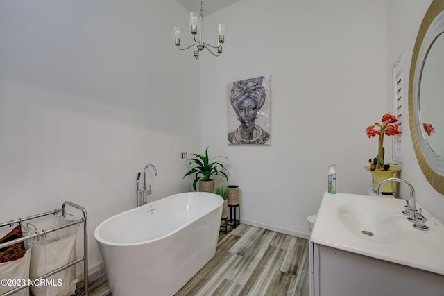 bathroom with hardwood / wood-style floors, a chandelier, vanity, toilet, and a bath