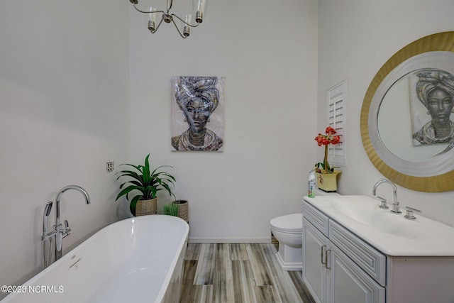 bathroom featuring hardwood / wood-style flooring, an inviting chandelier, a bathing tub, vanity, and toilet