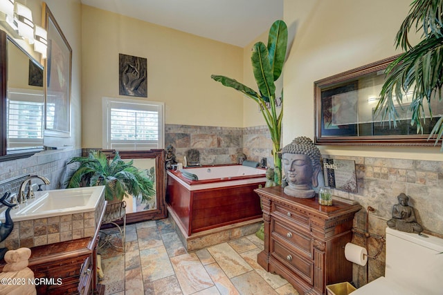 bathroom with sink and tiled bath