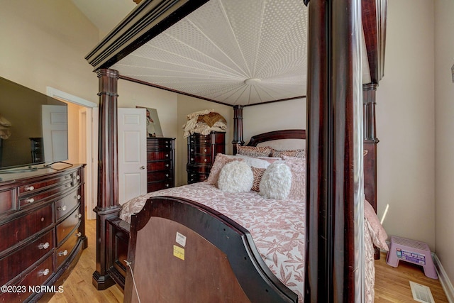 bedroom featuring light hardwood / wood-style floors and ornate columns