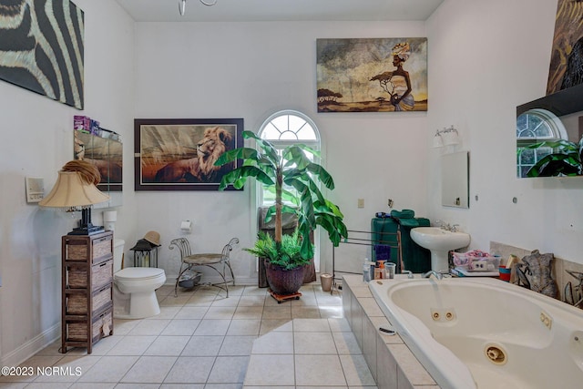 bathroom featuring tile patterned floors, toilet, sink, and tiled tub