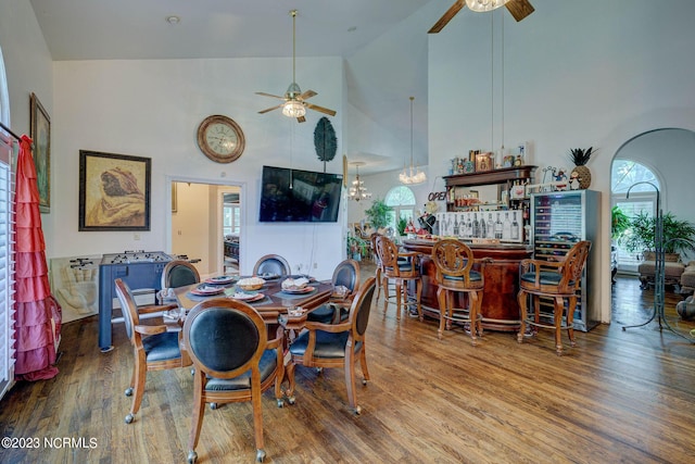 dining room featuring bar, wood-type flooring, high vaulted ceiling, and ceiling fan