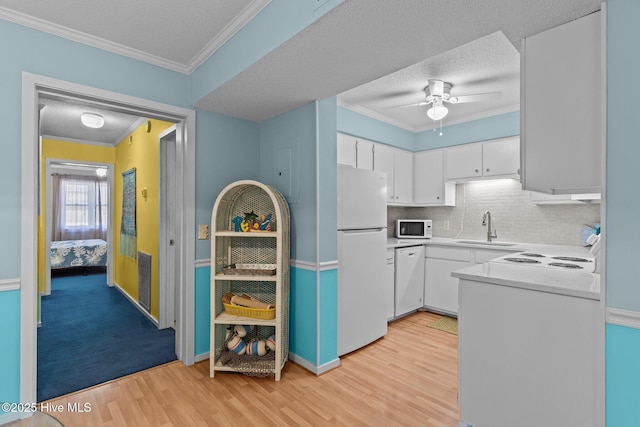 kitchen featuring sink, light wood-type flooring, white cabinets, crown molding, and white appliances