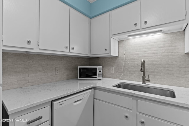 kitchen with white cabinetry, sink, decorative backsplash, light stone countertops, and white appliances