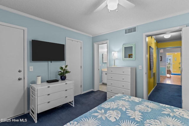 bedroom featuring dark colored carpet, ensuite bath, a textured ceiling, ornamental molding, and ceiling fan