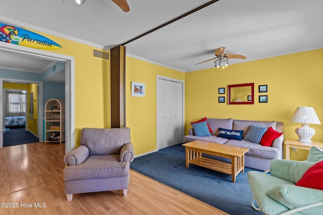 living room featuring ornamental molding, hardwood / wood-style floors, a textured ceiling, and ceiling fan