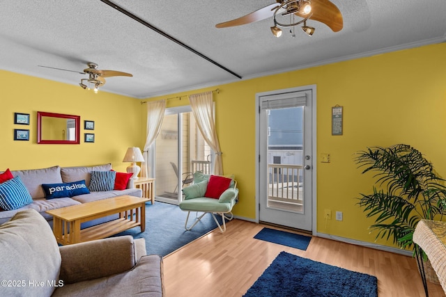 living room featuring a textured ceiling, light hardwood / wood-style flooring, ornamental molding, and ceiling fan