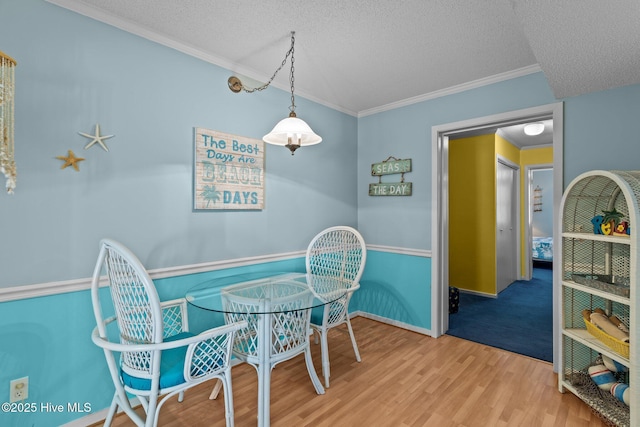 dining space featuring hardwood / wood-style flooring, crown molding, and a textured ceiling