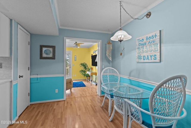 dining area featuring crown molding, wood-type flooring, and a textured ceiling