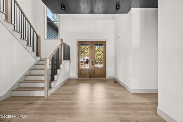 entryway featuring wooden ceiling, french doors, a high ceiling, and light wood-type flooring