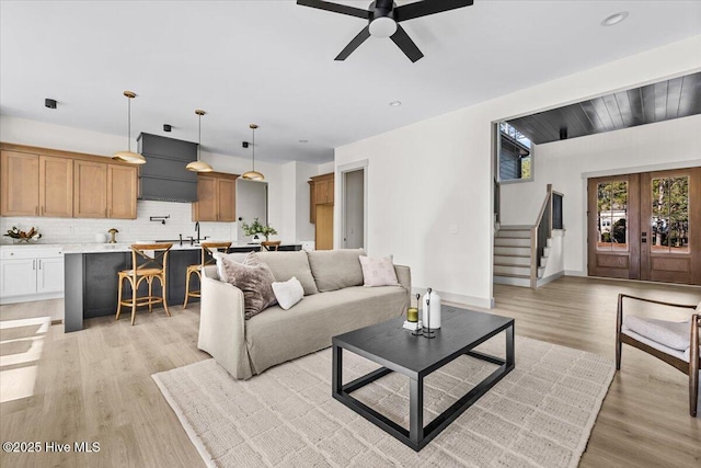 living room featuring french doors, ceiling fan, and light wood-type flooring