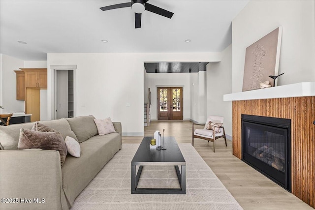 living room featuring ceiling fan, light wood-type flooring, and french doors