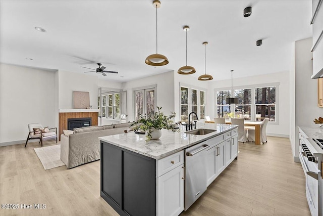 kitchen featuring appliances with stainless steel finishes, sink, white cabinets, hanging light fixtures, and light stone counters