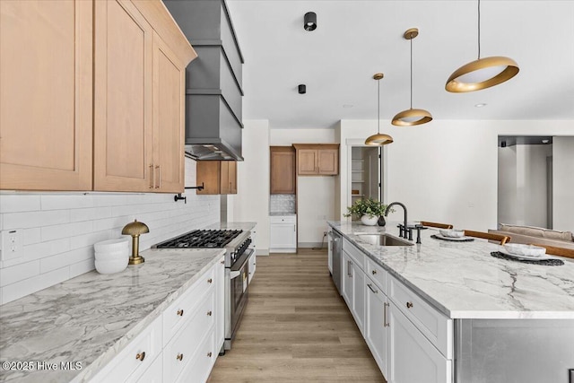 kitchen with appliances with stainless steel finishes, decorative light fixtures, an island with sink, sink, and white cabinets