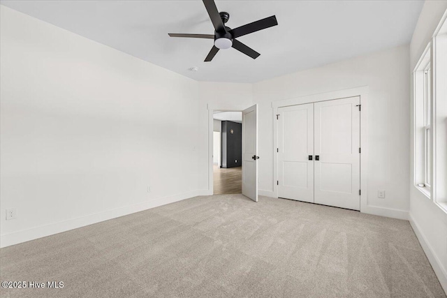 unfurnished bedroom featuring light carpet, ceiling fan, and a closet