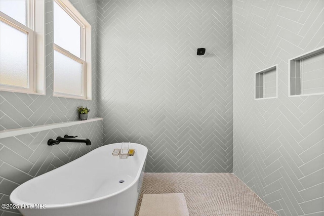 bathroom with a bath and tile walls