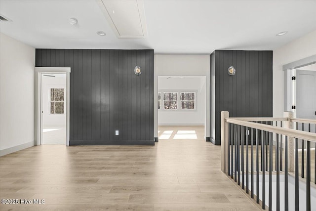 hallway with light hardwood / wood-style floors and wood walls