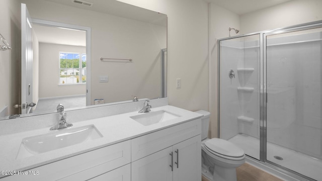 bathroom with a stall shower, a sink, toilet, and double vanity