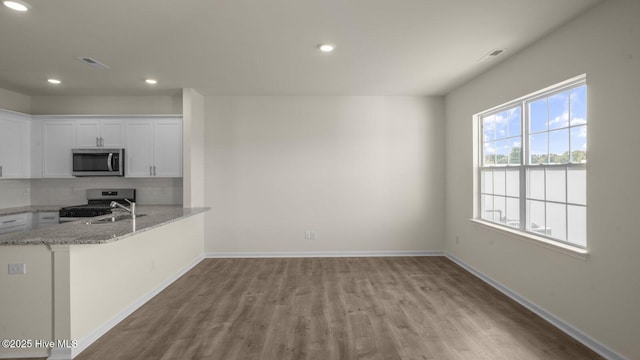 kitchen featuring tasteful backsplash, visible vents, appliances with stainless steel finishes, light stone counters, and white cabinetry