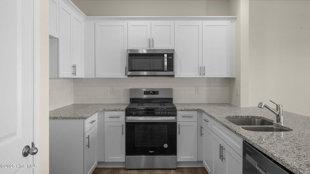 kitchen featuring stainless steel appliances, light stone counters, a sink, and white cabinets