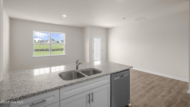 kitchen featuring light stone countertops, white cabinets, a sink, wood finished floors, and dishwasher