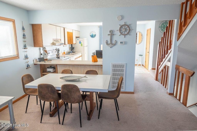 carpeted dining area featuring sink and a textured ceiling