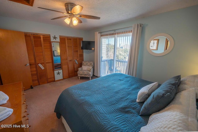 bedroom featuring ceiling fan, carpet floors, a textured ceiling, and two closets