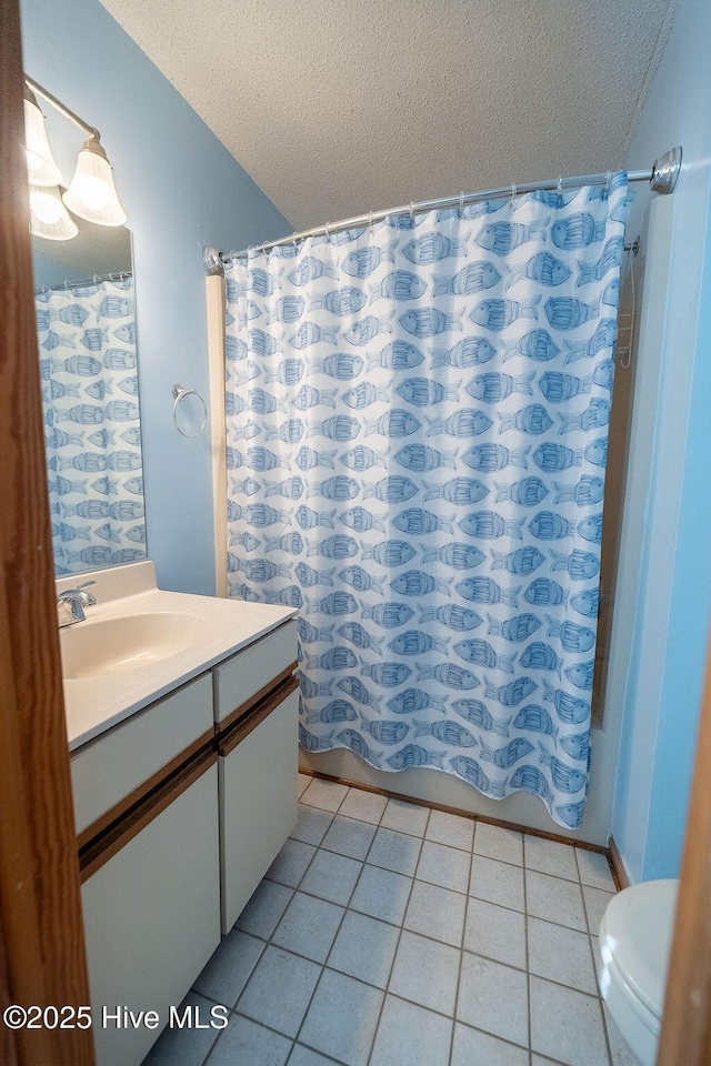 full bathroom featuring tile patterned flooring, vanity, a textured ceiling, and toilet