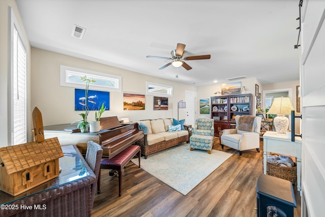 living room featuring dark wood-type flooring and ceiling fan