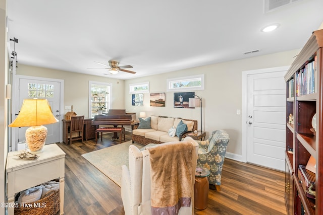 living room featuring dark wood-type flooring and ceiling fan