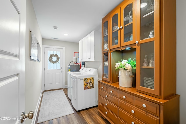 laundry area with cabinets, washing machine and clothes dryer, and dark hardwood / wood-style floors