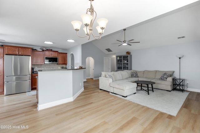 living room featuring ceiling fan with notable chandelier, vaulted ceiling, and light wood-type flooring