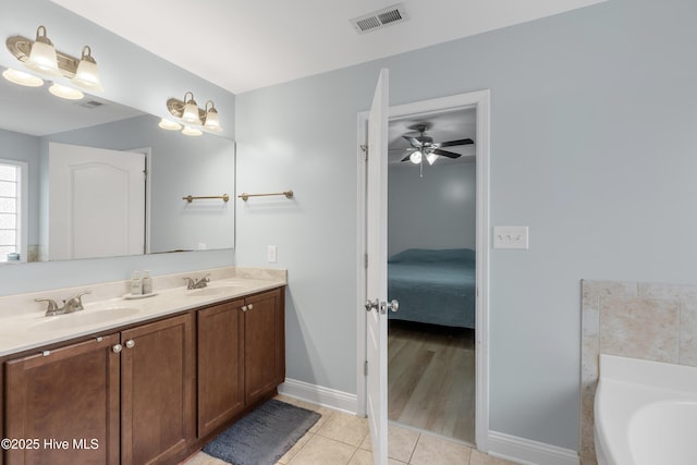 bathroom with tile patterned flooring, a tub to relax in, and vanity