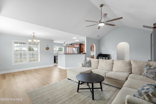 living room with lofted ceiling, ceiling fan with notable chandelier, and light hardwood / wood-style flooring