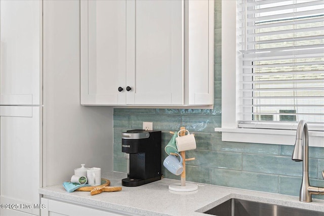 interior details featuring backsplash, sink, and white cabinets