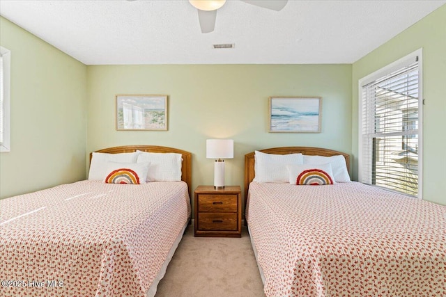 bedroom featuring ceiling fan, light colored carpet, and a textured ceiling