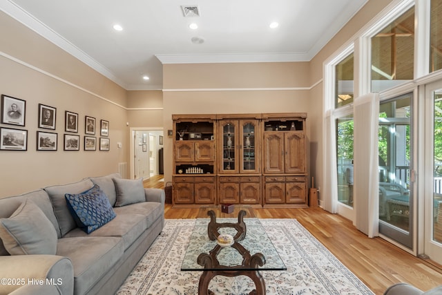 living room with ornamental molding and light hardwood / wood-style flooring